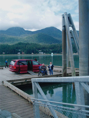 A picture of two men one in a wheelchair fishing on an accessible pier in Alaska.