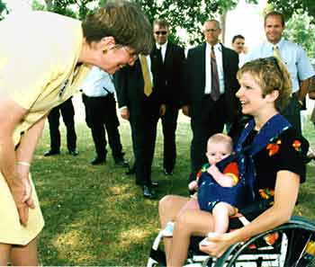 Janet Reno speaks to mother using a wheelchair and her baby