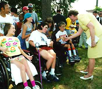 Janet Reno shakes hands with children who use wheelchairs