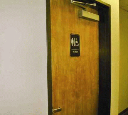 Toilet room signage incorrectly positioned on door