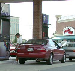 a person is putting fuel into their automoble at a fuel pump