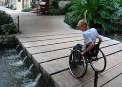 photo - woman using wheelchair rolls over bridge at River Walk