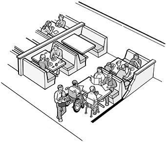 In a restaurant with booth seating, a man using a wheelchair is seated at an accessible table with three companions.
