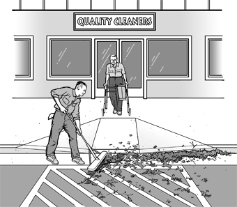 As a customer using a walker exits a dry cleaner's, an employee is brushing leaves away from the curb ramp area.