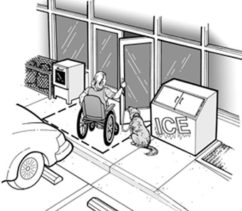 A woman in a wheelchair, with a service animal, is opening the door to a convenience store. The store’s ice machine and newspaper box are out on the sidewalk, but they are away from the door, so they do not block her entrance.